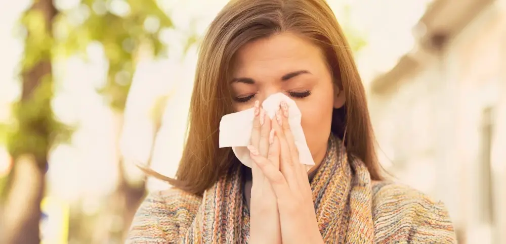 woman blowing her nose outside